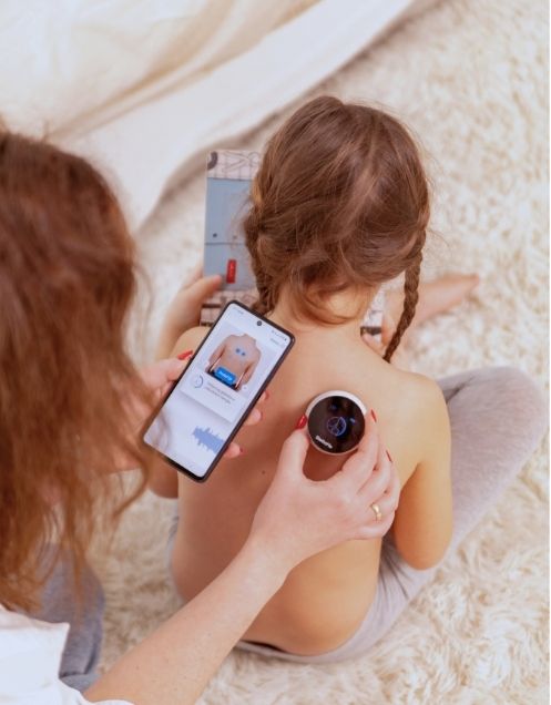 Mother using StethoMe to check her daughter's breathing